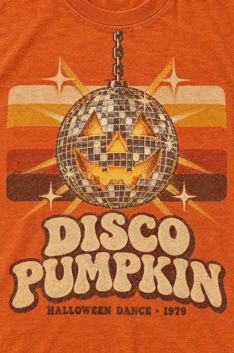 Orange tee printed with a mirror disco ball carved like a jack-o’-lantern in front of 1970s stripes, words Disco Pumpkin, Halloween Dance 1979