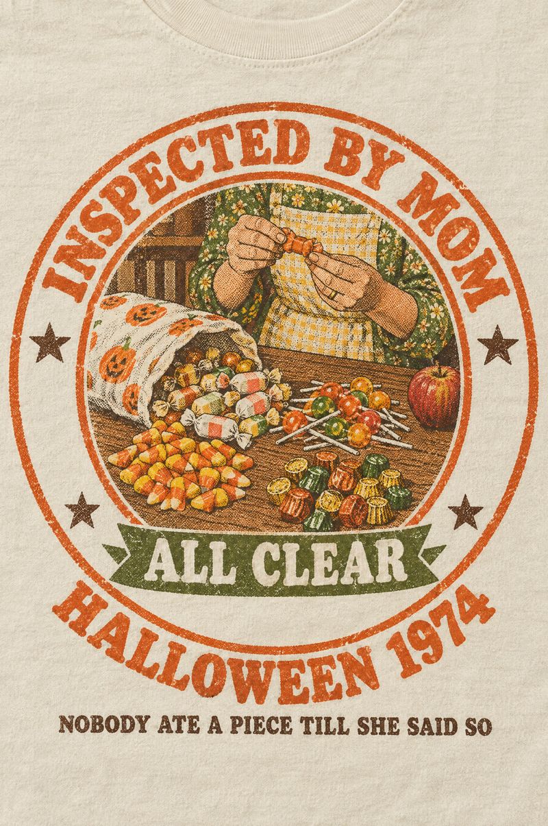 Ivory tee printed with a round rubber-stamp seal reading Inspected by Mom, Halloween 1974, around Mom’s hands checking candy at the kitchen table, a banner reading All Clear, and the words Nobody Ate a Piece Till She Said So
