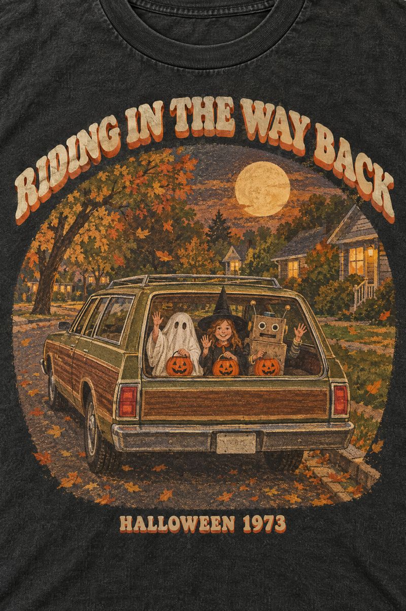 Washed black tee printed with a wood-paneled station wagon at dusk, three kids in ghost, witch and cardboard robot costumes waving out the back window, words Riding in the Way Back, Halloween 1973